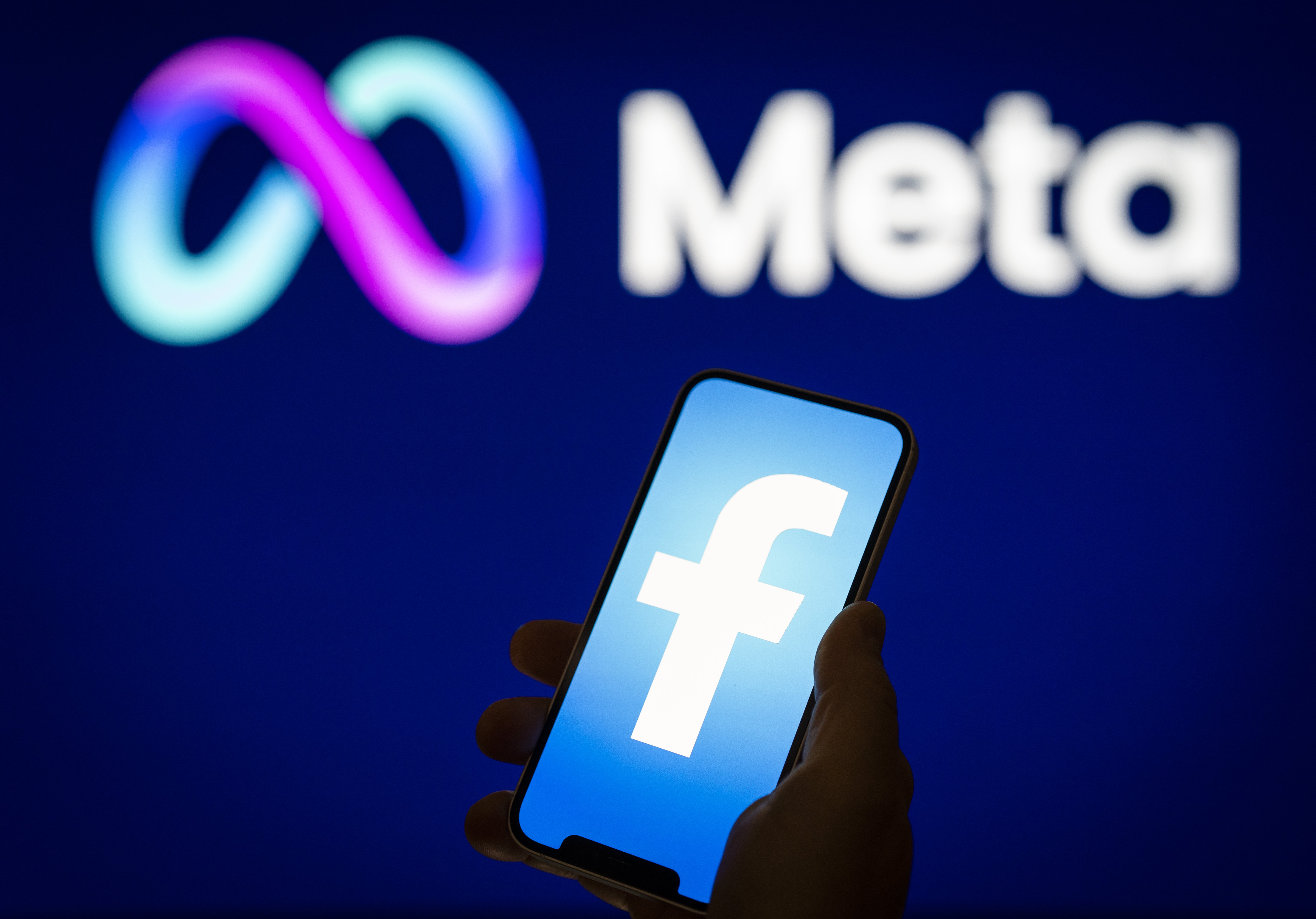 A Facebook logo is seen on a mobile device screen with a Meta logo in the background in this photo illustration on 31 May, 2023 in Warsaw, Poland.