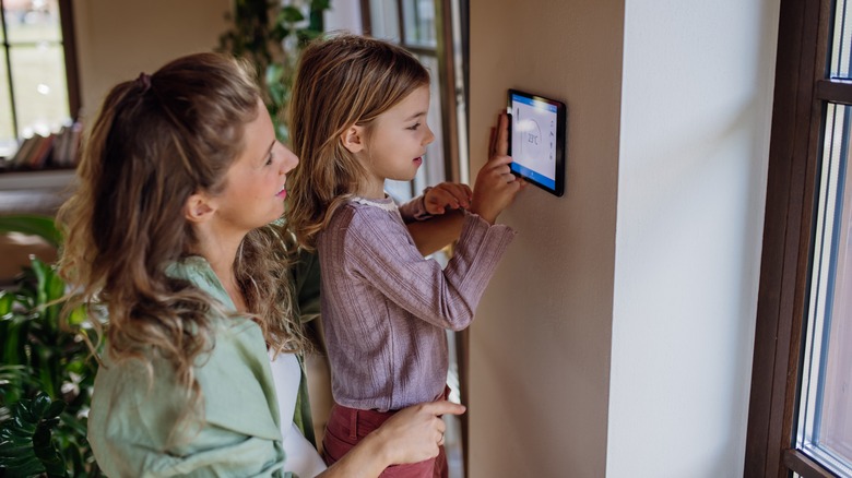 Child adjusting the temperature on the smart thermostat