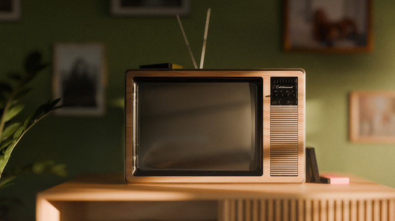 Old CRT tv positioned on a table in front of a green wall