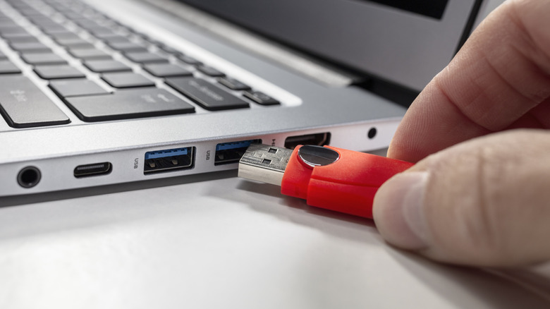 An image showing someone connecting a flash drive to a USB port.