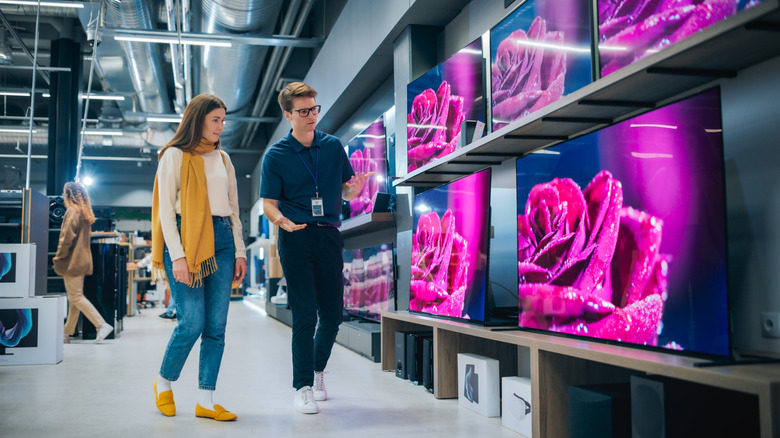A woman is selecting a TV, assisted by a sales associate.