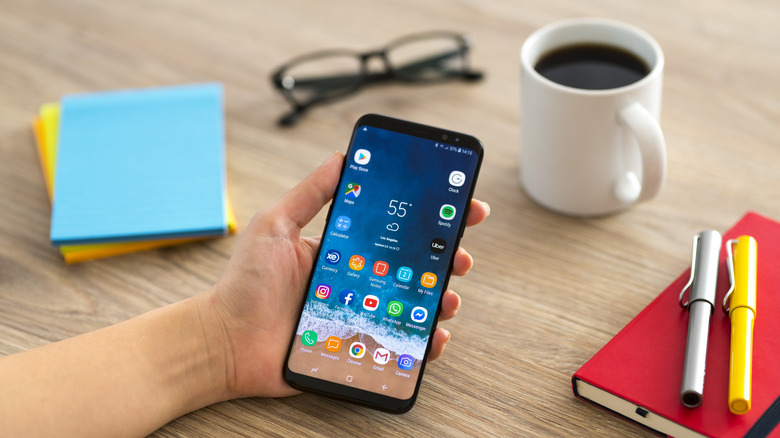 Android phone shown in hand displaying app selections