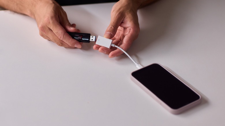 A person plugging in a flash drive into a phone