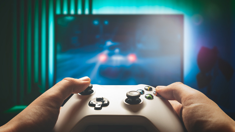 Two hands hold a controller in front of a TV while playing a video game.