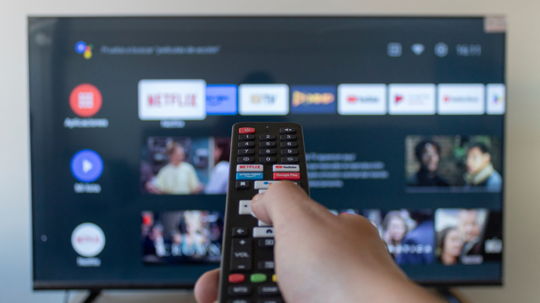 Individual holding a remote in front of a smart TV