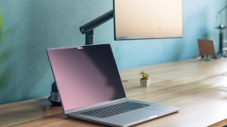 A laptop beside a display on a mounting arm