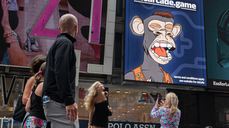 A billboard of a Bored Ape Yacht Club NFT as people walk by