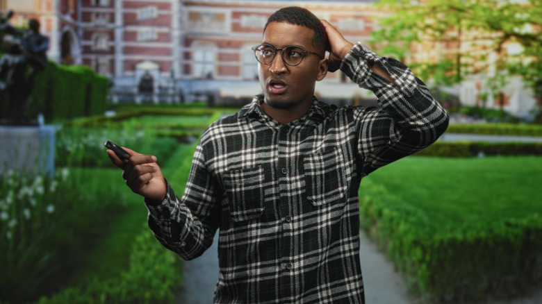 A person holding a car key fob looking perplexed.