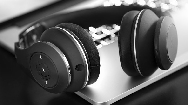 Wireless headphones resting on top of a laptop.