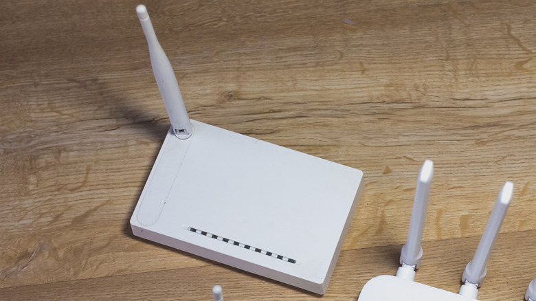 an old white router with a single antenna situated on a wooden surface