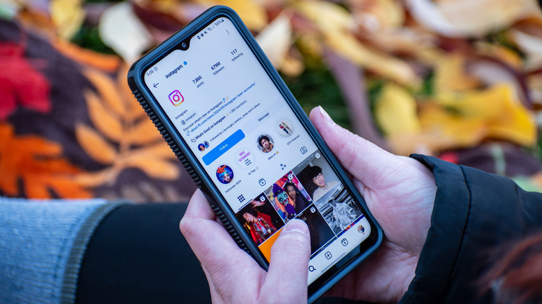 A person holding a phone with Instagram displayed on the screen.